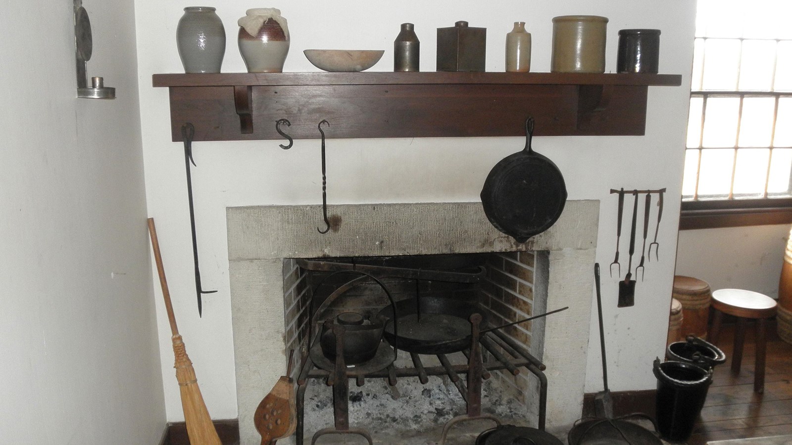 Fireplace with wooden shelf and various implemtents to the side and above