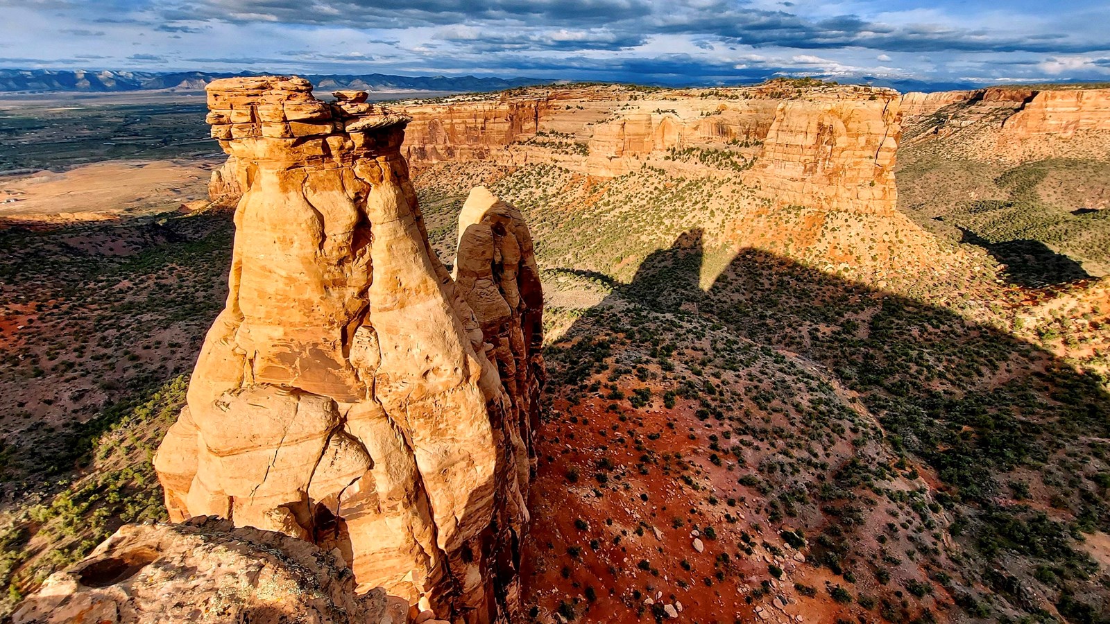 a sandstone monolith towers over forested canyons hundreds of feet below