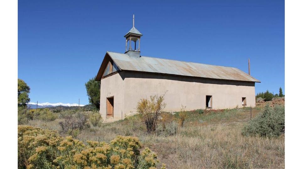 side view of a plain church building surrounded by tall grass and landscape  