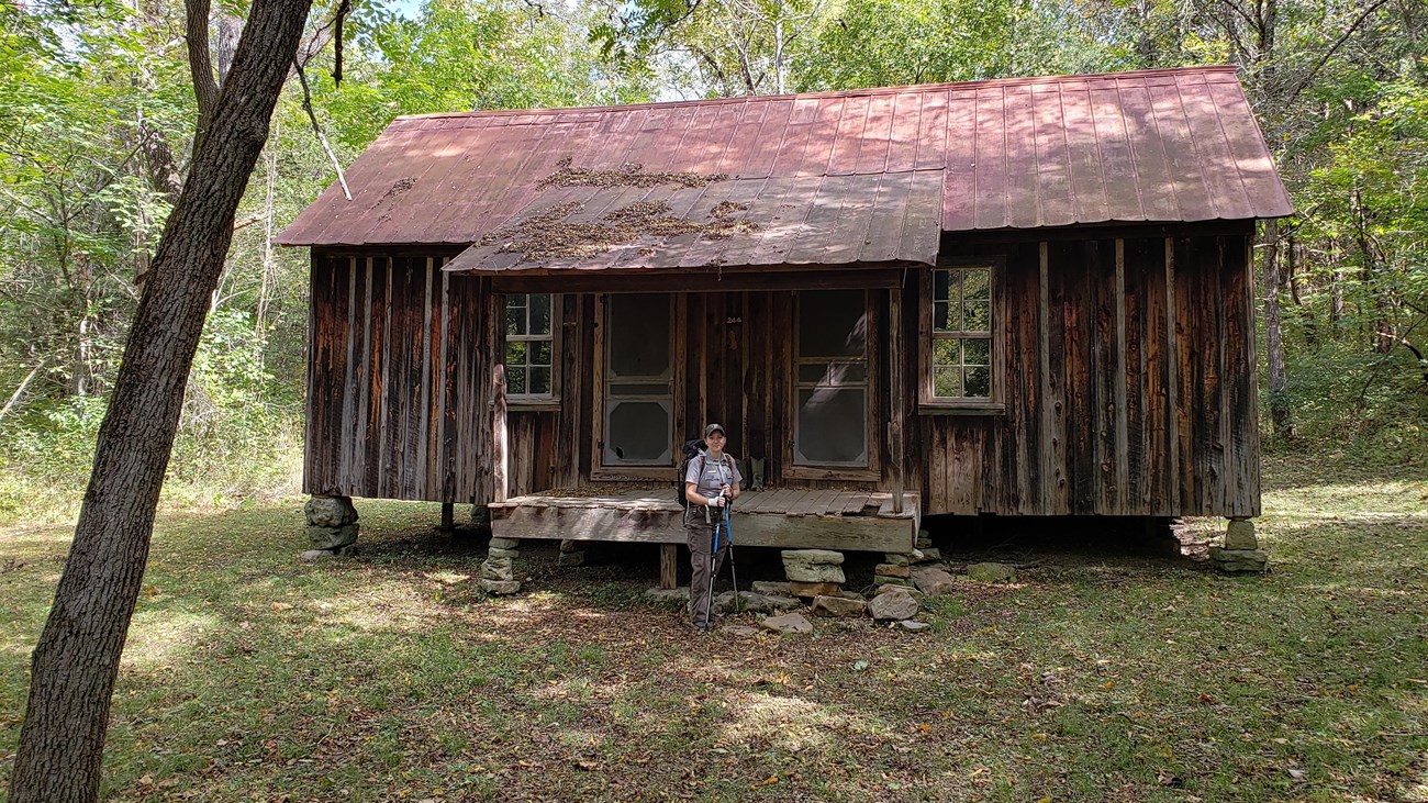 an old cabin with weathered brown wood siding running up and down, tin roof rusted and ranger