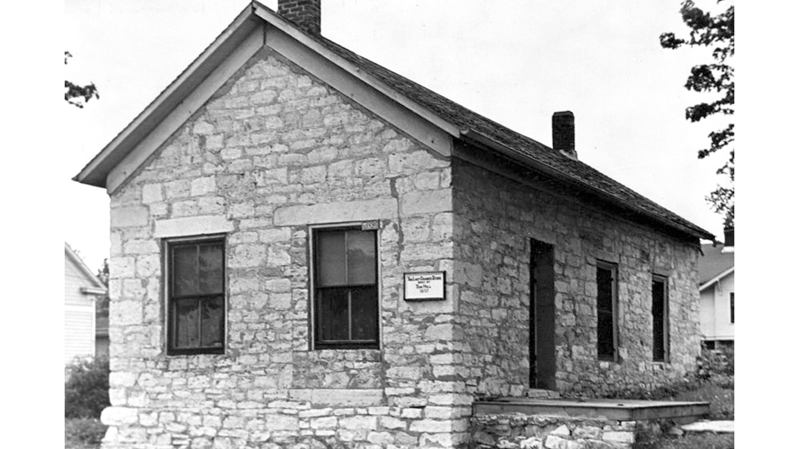 one-story stone building with a shingled roof. 