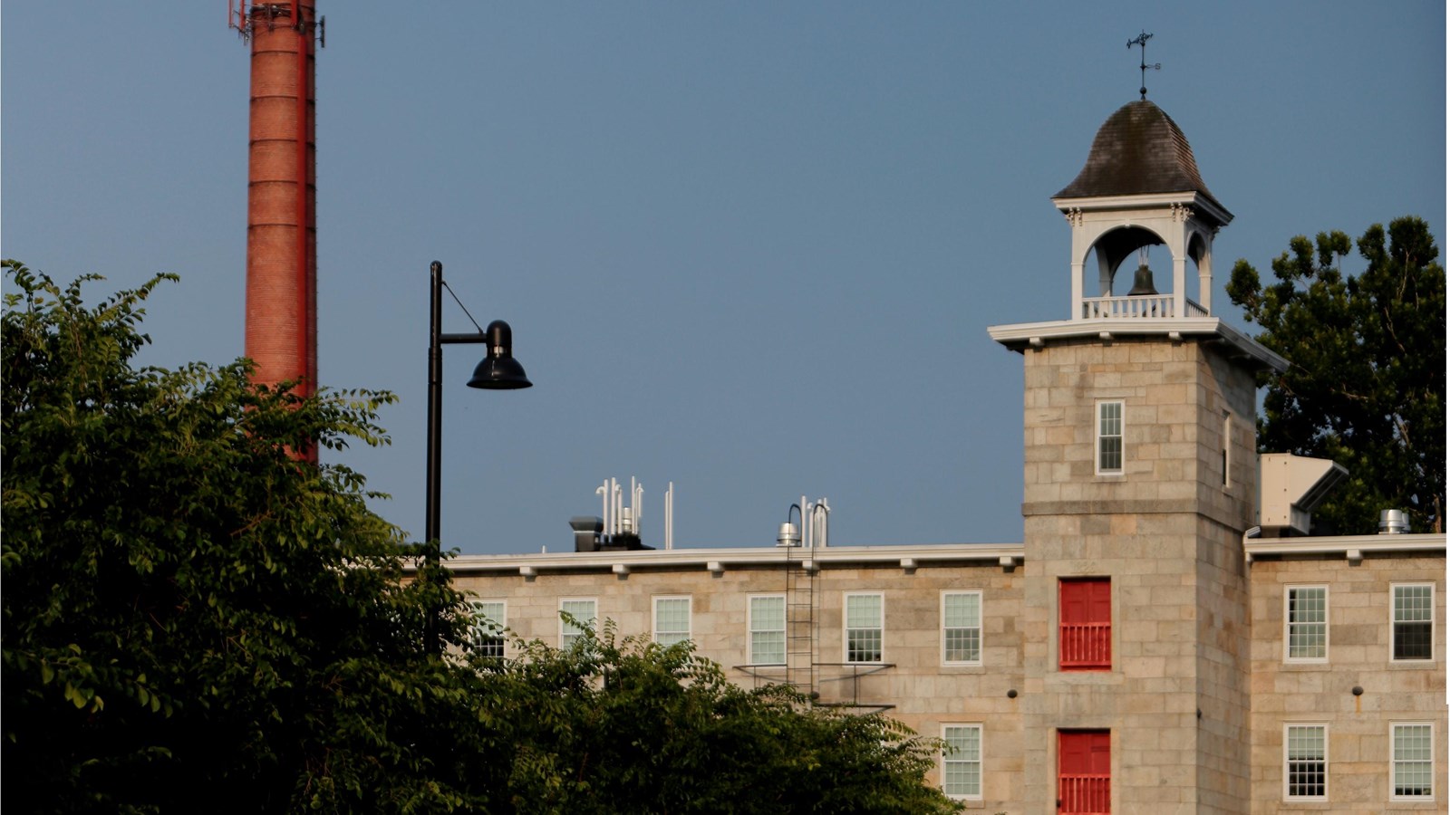Prominent stone mill with bell tower with trees in the foreground