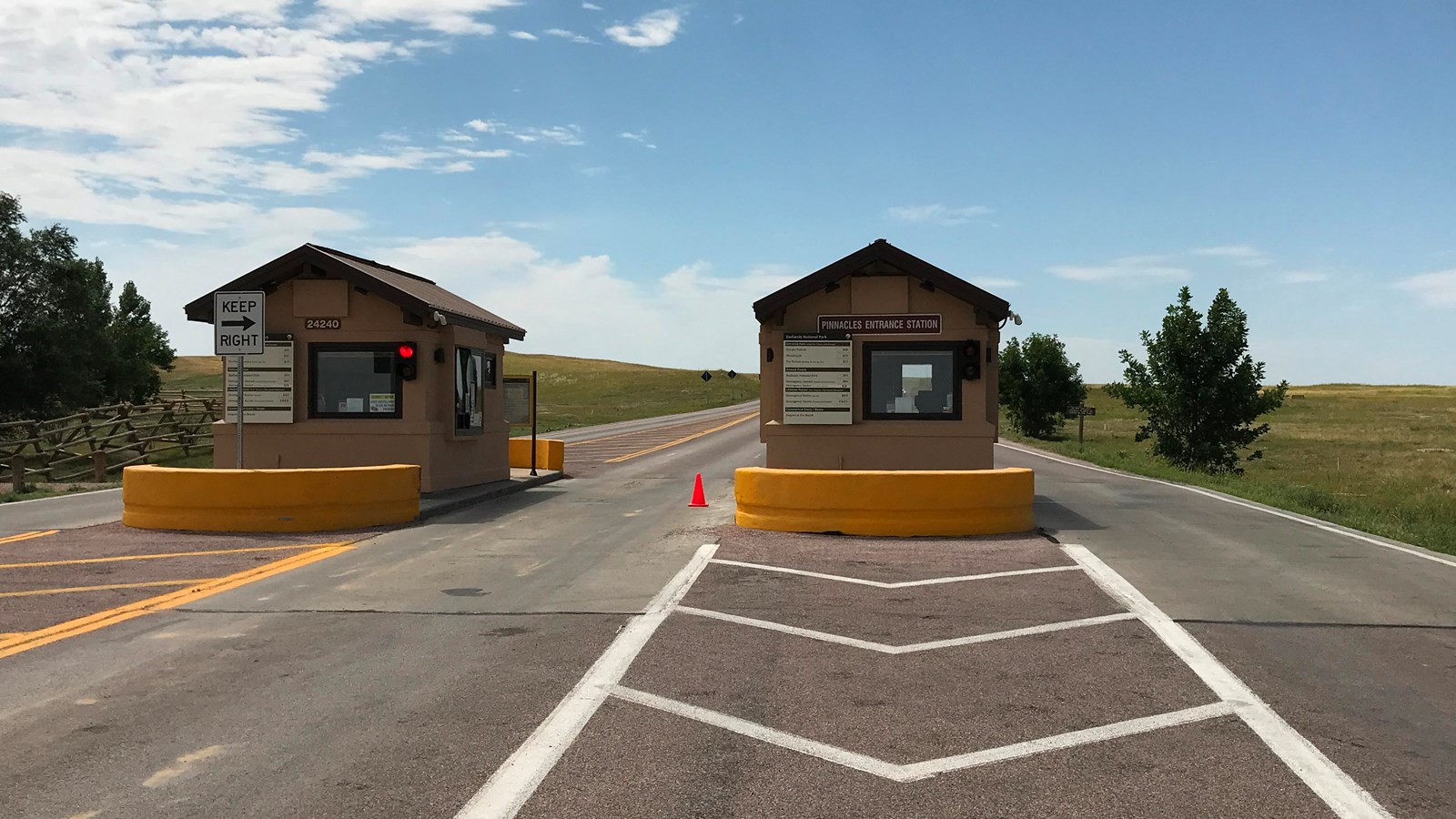 Two tan buildings in the middle of paved road under blue sky.