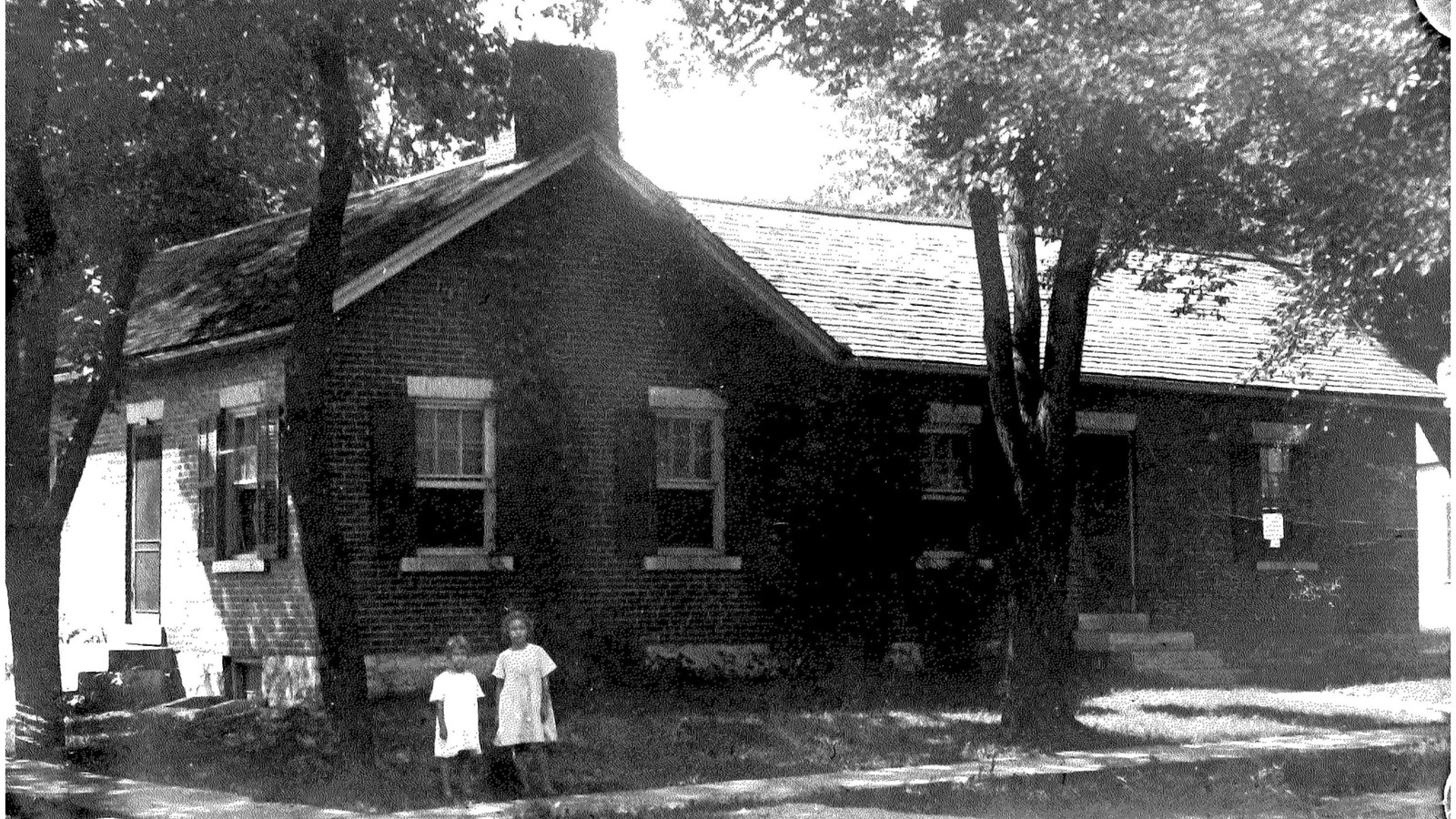 One-story brick house. In front stone steps lead up to a central door. 