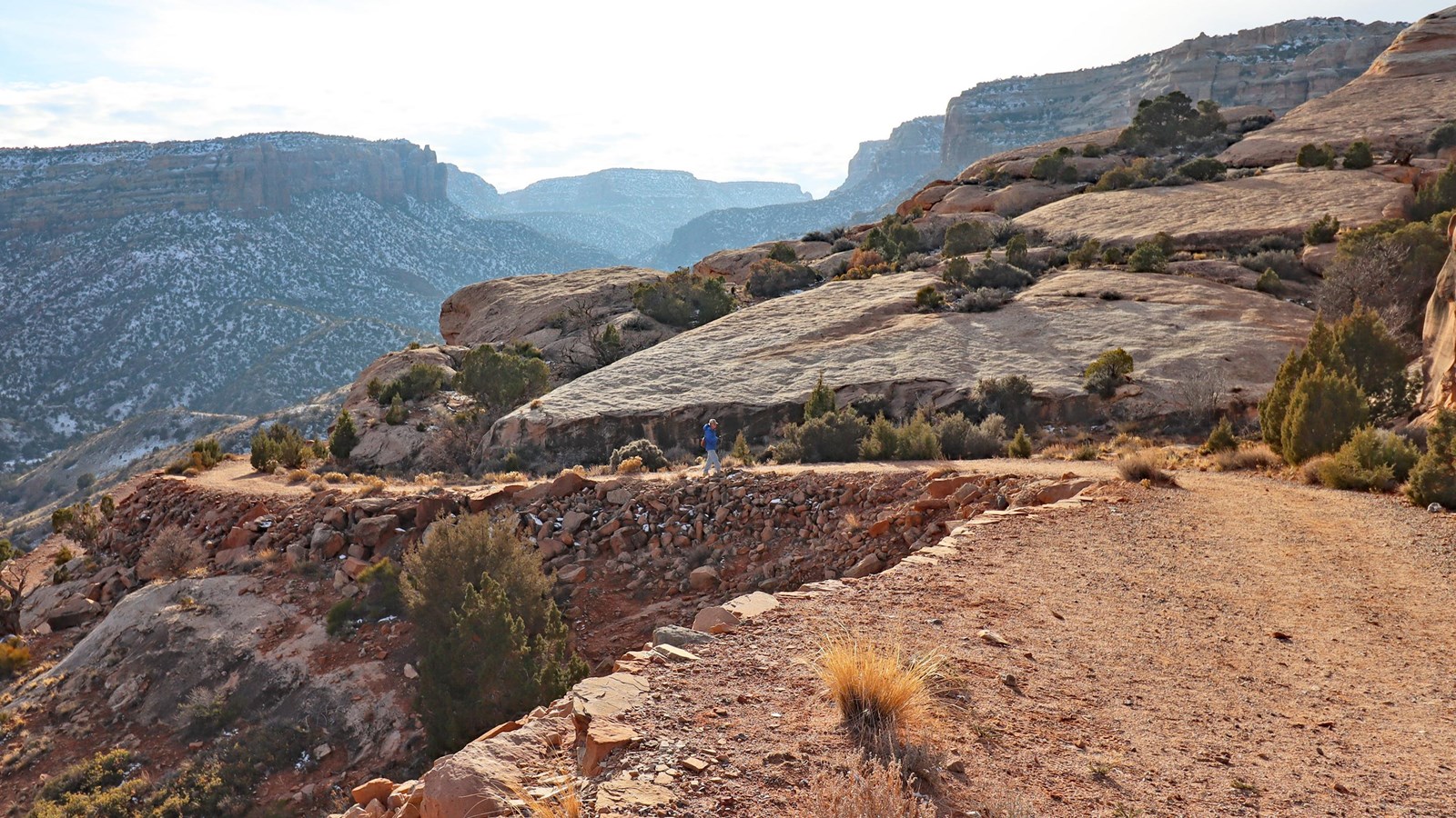 winding sandy path ascends a long ramp with views of forested canyons