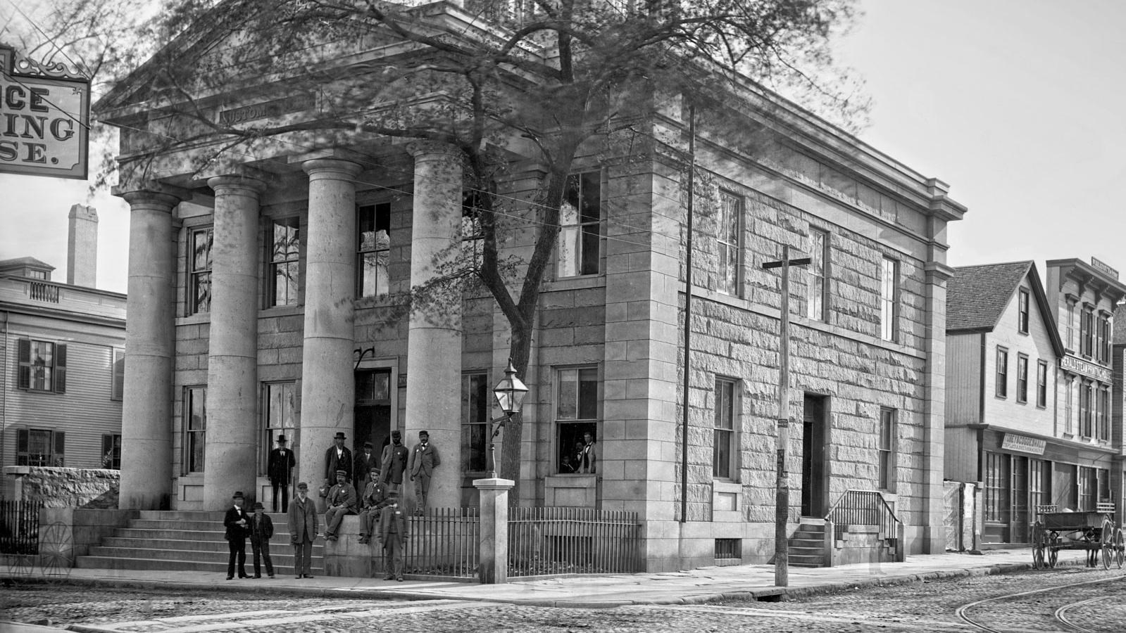 Historic photo of the U.S. Custom House in New Bedford with a group of people standing in front.