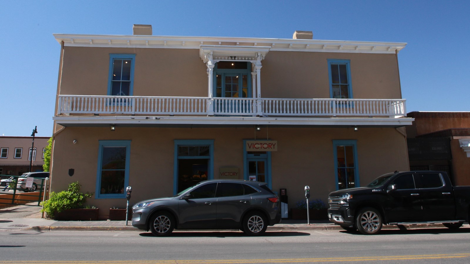 A historic looking two story adobe home, with an upstairs veranda.