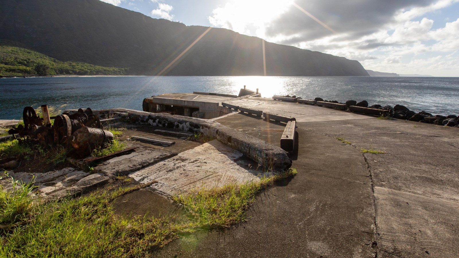 A short cement dock, ocean, and sea cliffs