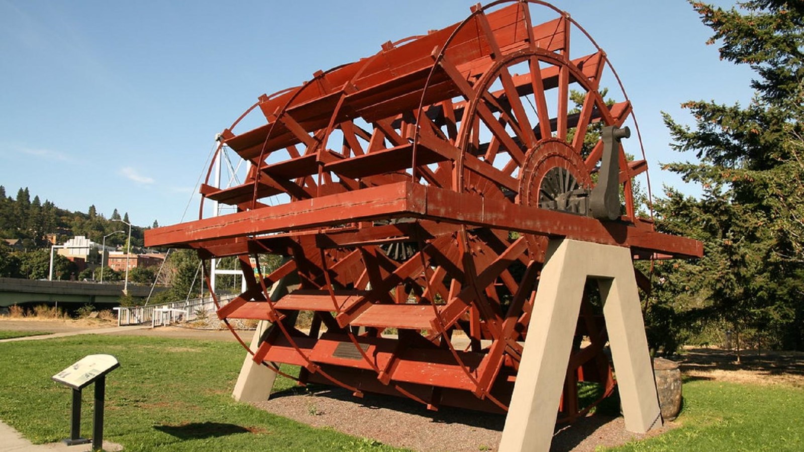 A large red paddlewheel from a river boat sits on display on a green lawn