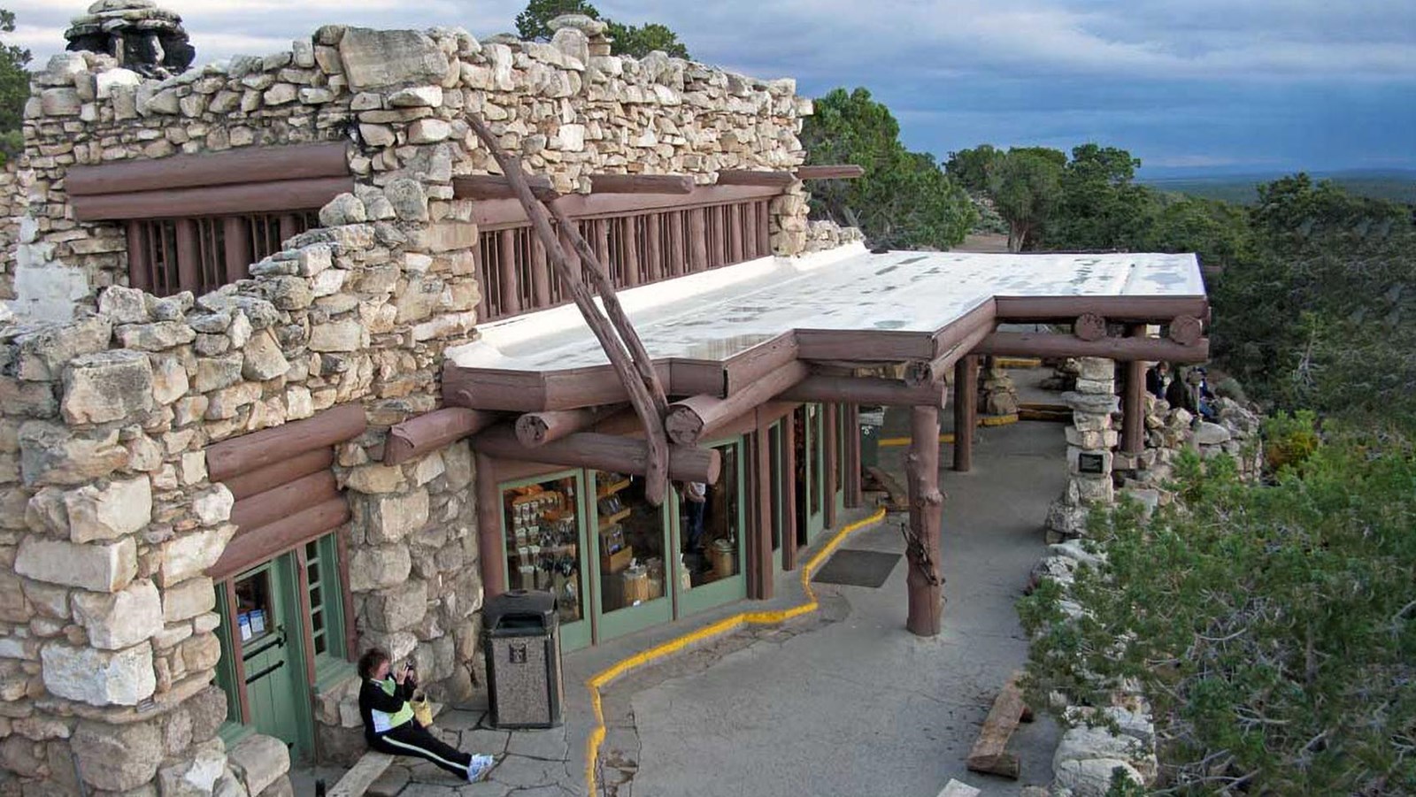 a roughhewn building made of rocks and logs with a porch with an overhanging roof above the entrance