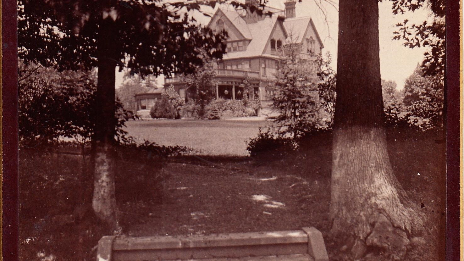 House in distance, steps in front flanked by trees