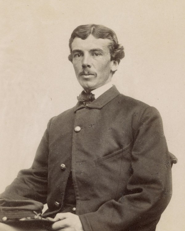 A young Civil War cavalry officer poses seated in uniform.