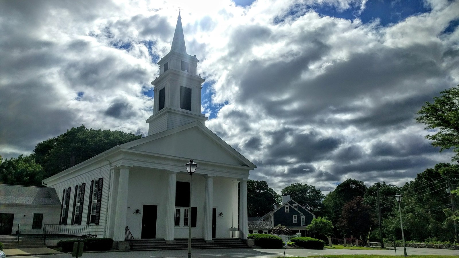 White church with sun and clouds visible in the sky