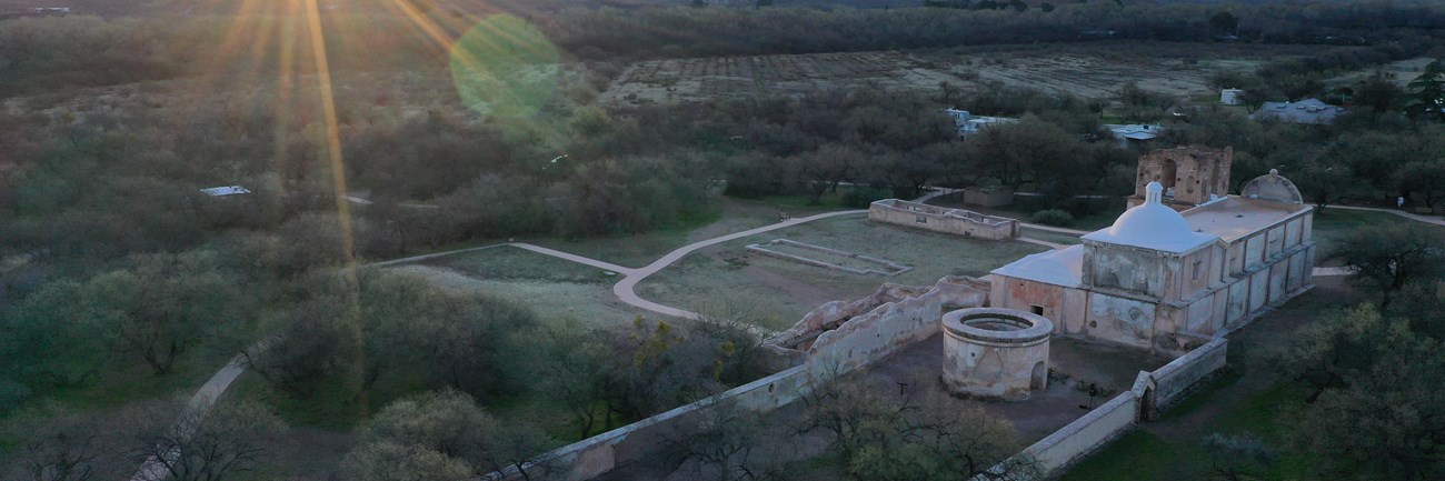 aerial photo of mission grounds with sunrise over mountains in the distance