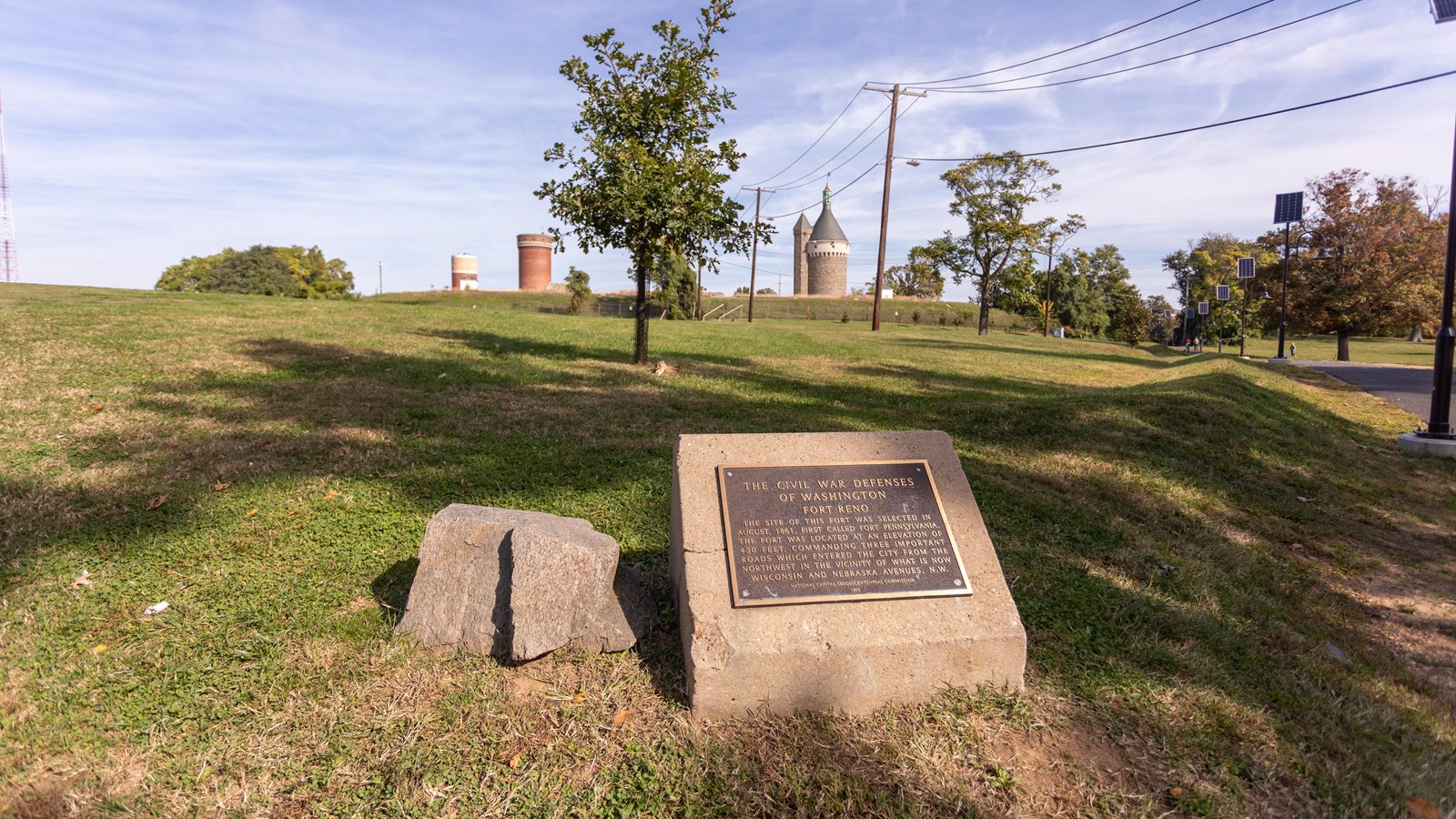A plaque on a stone in front of a grassy field.