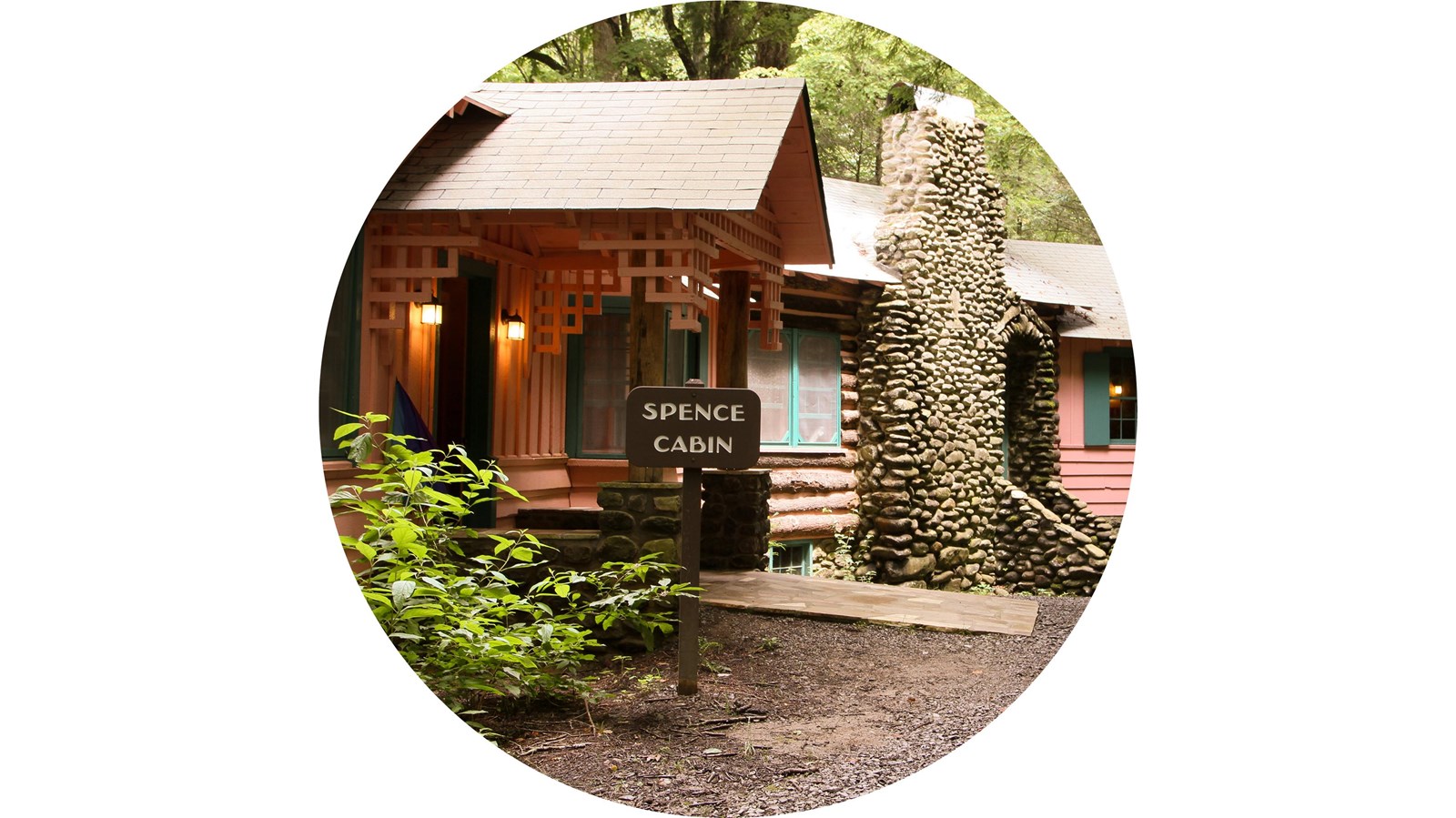 A single-story pink sided cabin with green shutters.