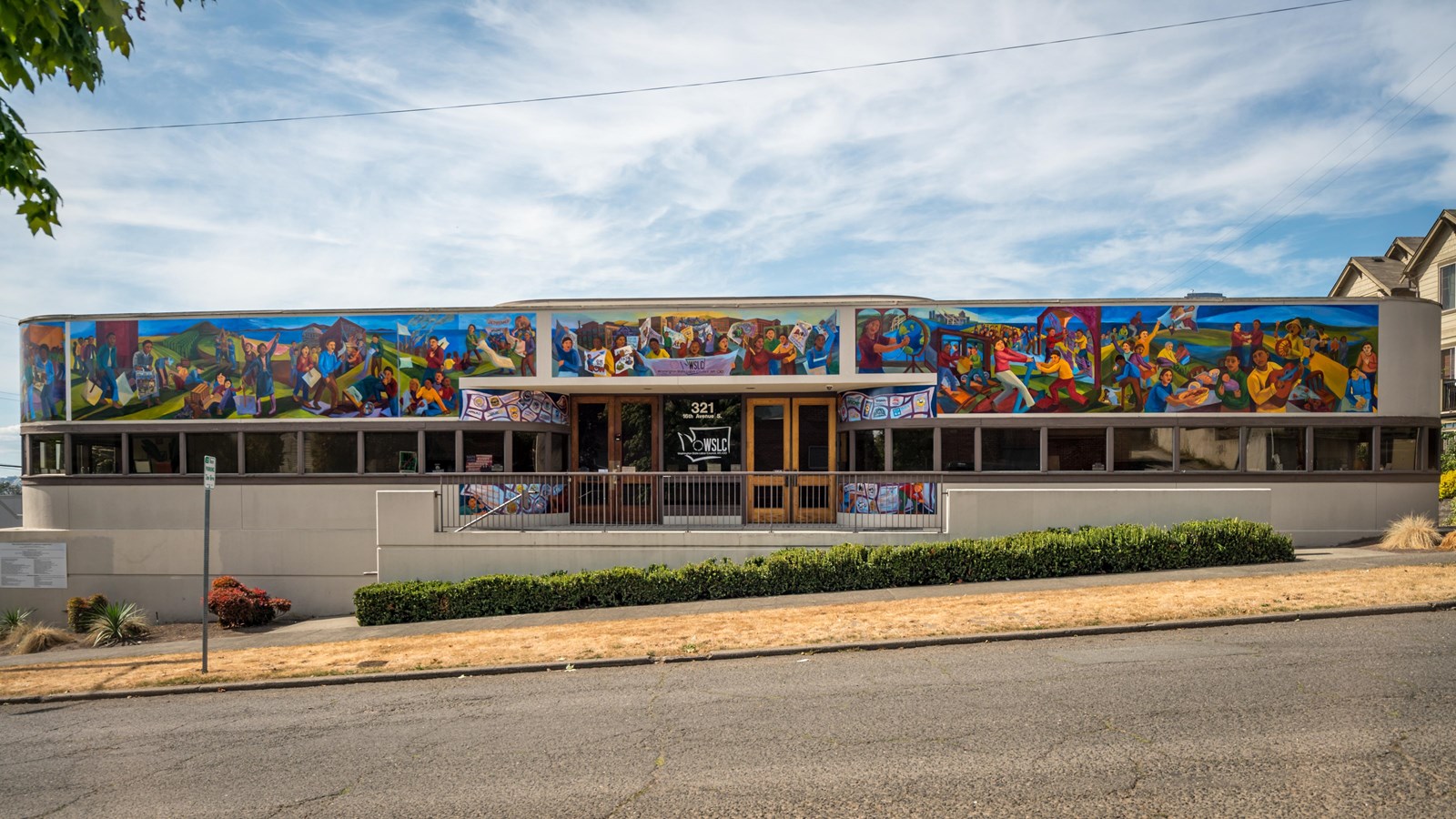 The mural spans the upper portion of a modern building, showcasing a series of vibrant scenes.