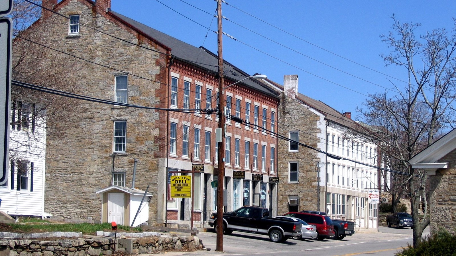 Brick buildings with cars and telephone wires in foreground