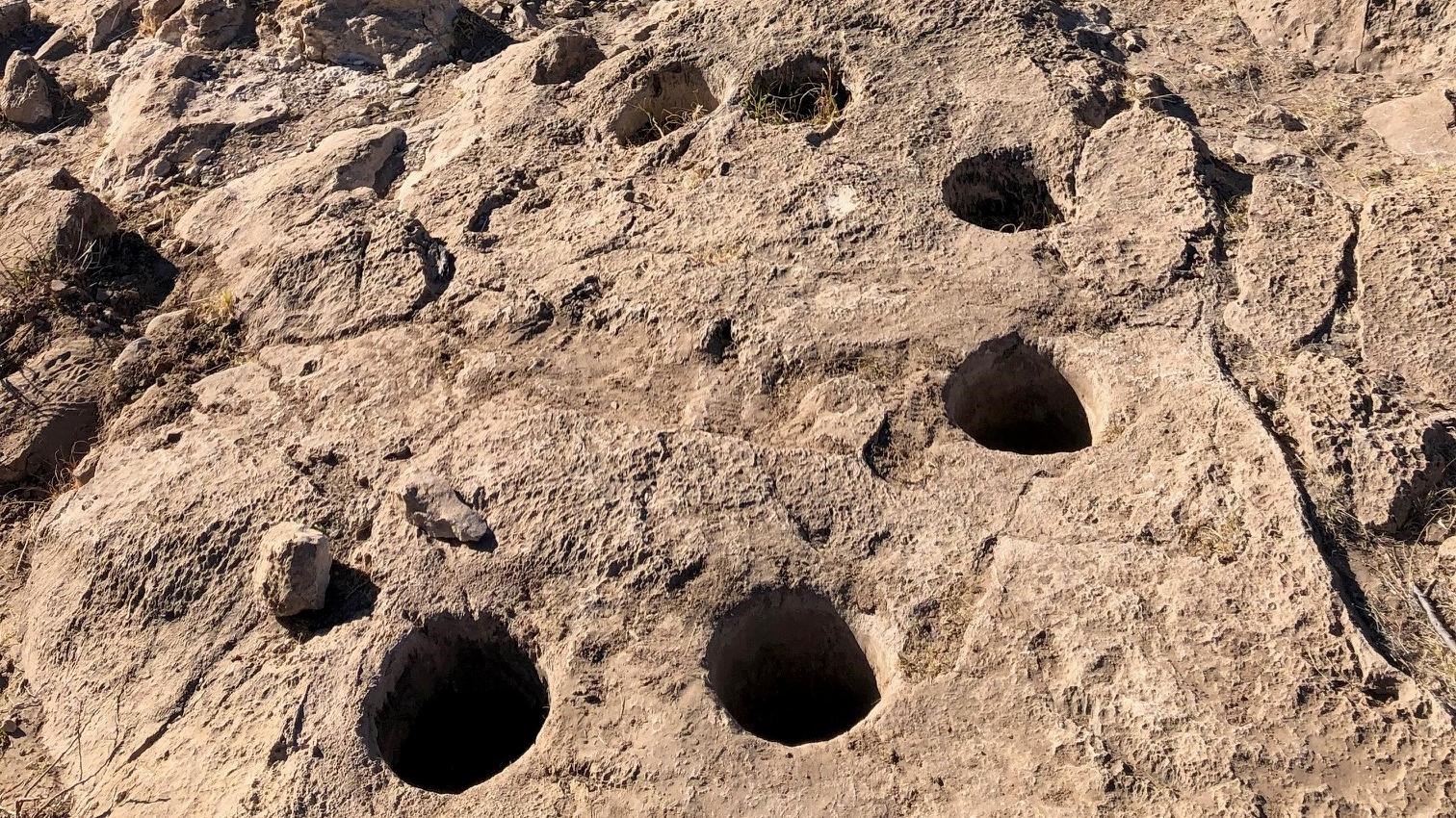 Six holes about five inches in diameter are laid out in a circle in a limestone ledge.