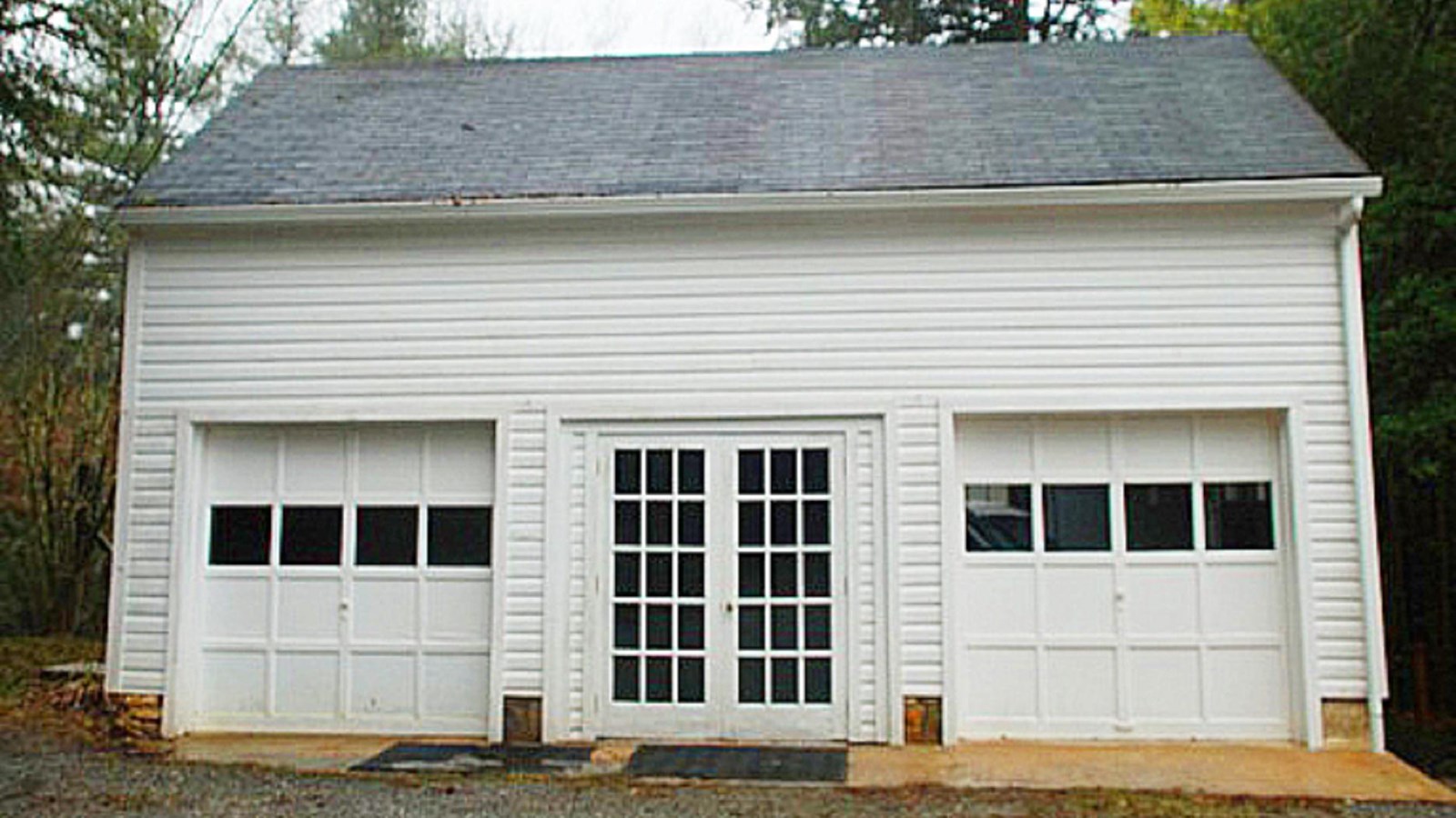 White garage building with french doors in the middle and garage doors on each side
