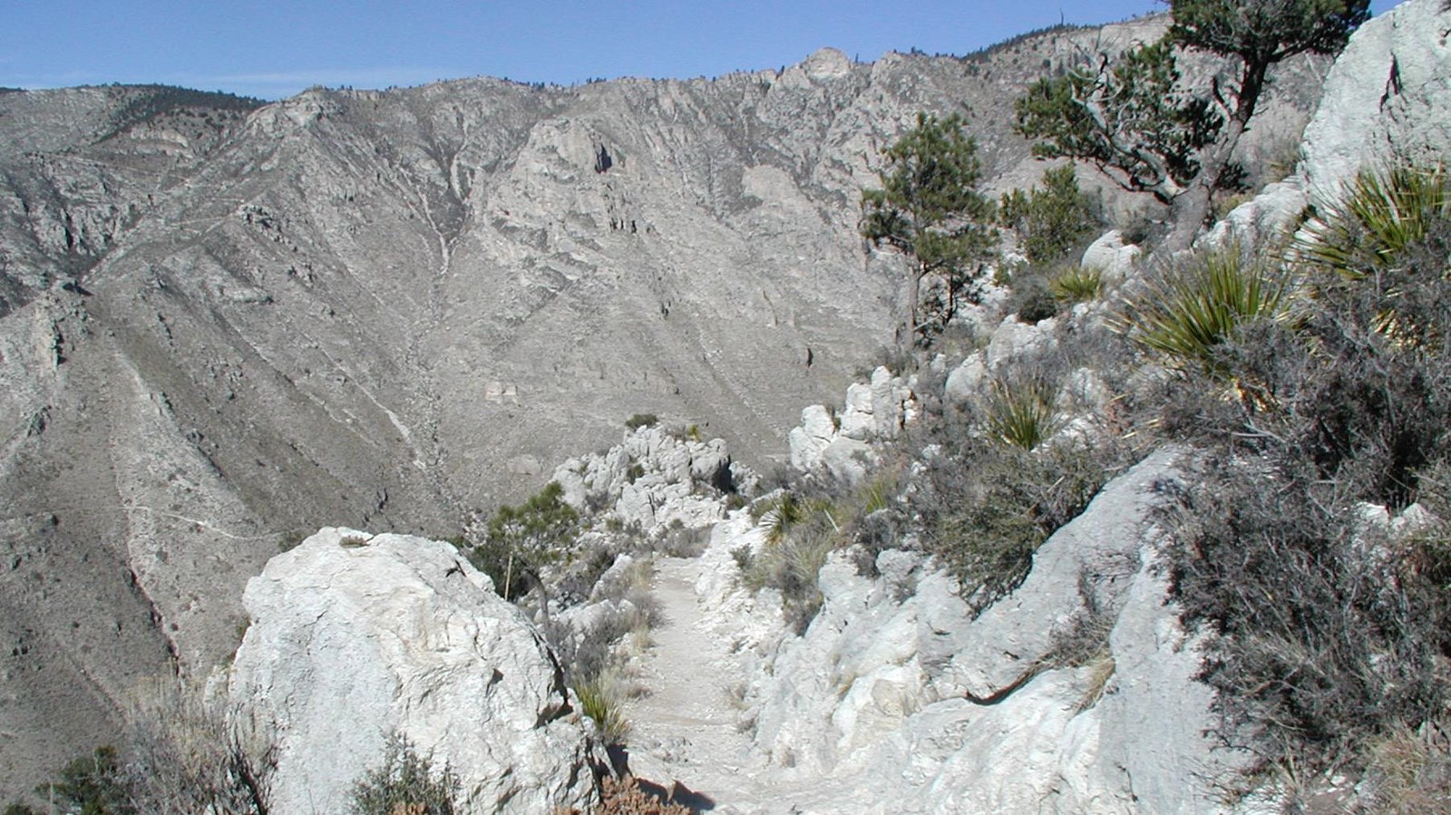 Looking down at where a trail curves around a steep ridgeline