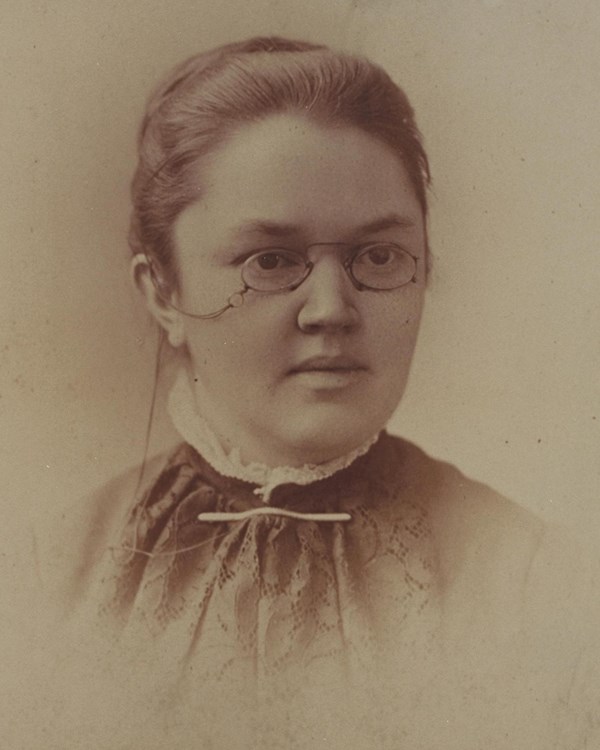 Head and shoulders portrait of woman wearing glasses.
