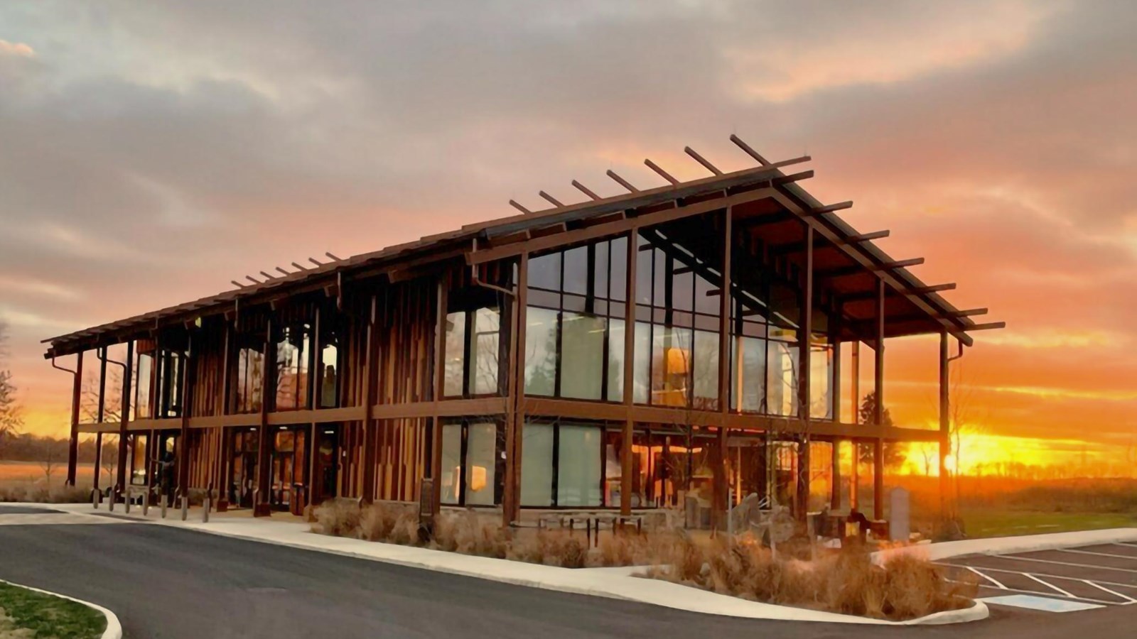 Exterior of two-story building of glass and metal resembling a wood long house structure.