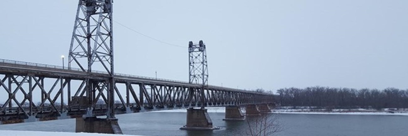Yankton Double Decker Meridian Bridge over Missouri River. Snow on the ground and covering the bench