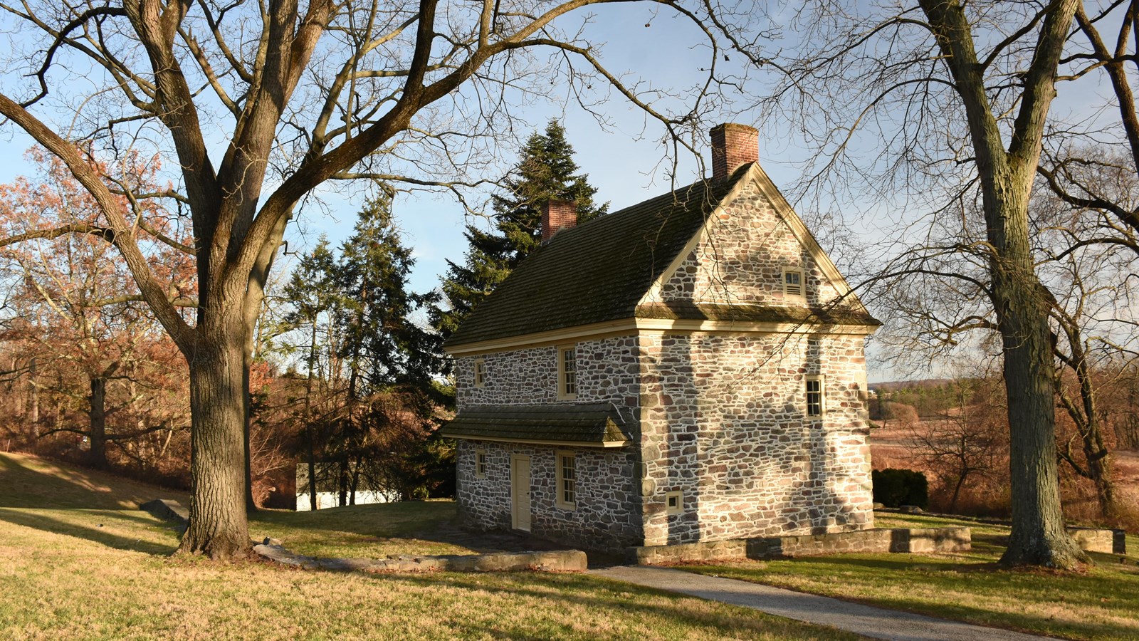photograph, outdoors, two-story stone house, trees.