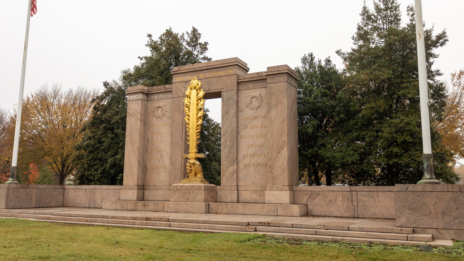 Sculpture of a golden flaming sword flanked by granite walls.