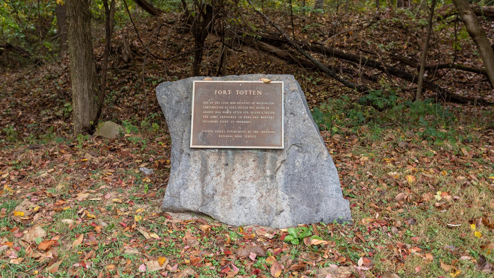 A plaque on a rock in a wooded area. 