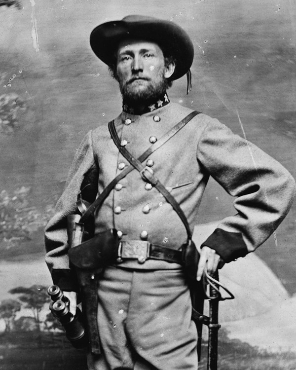 A cavalryman in uniform poses for a full body studio portrait.