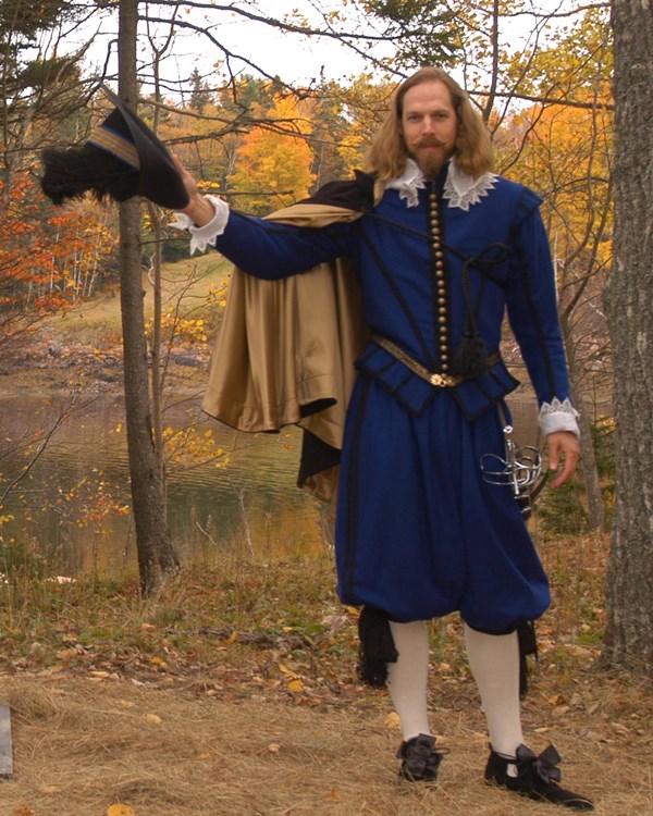 An interpreter in a blue costume stands next to a statue in the same pose