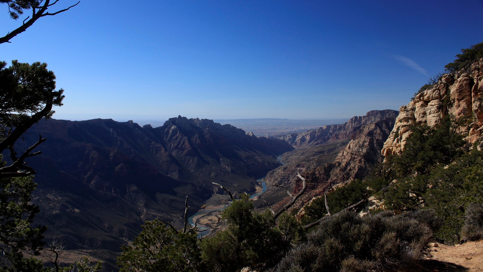 A vast overlook looking into a mountainous canyon with a river cutting through.
