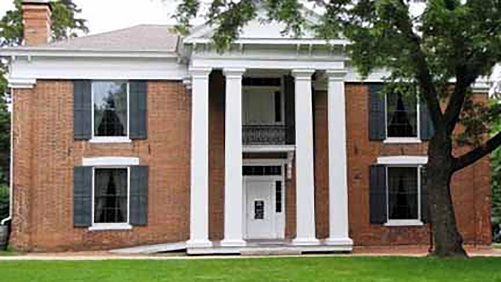 Historic brick, two story home, with large white, front pillars around the porch.