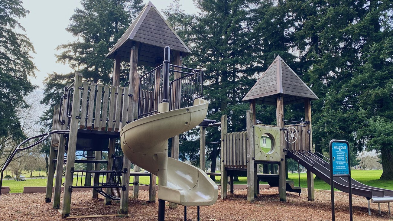 A large play structure in a bark chip playground.