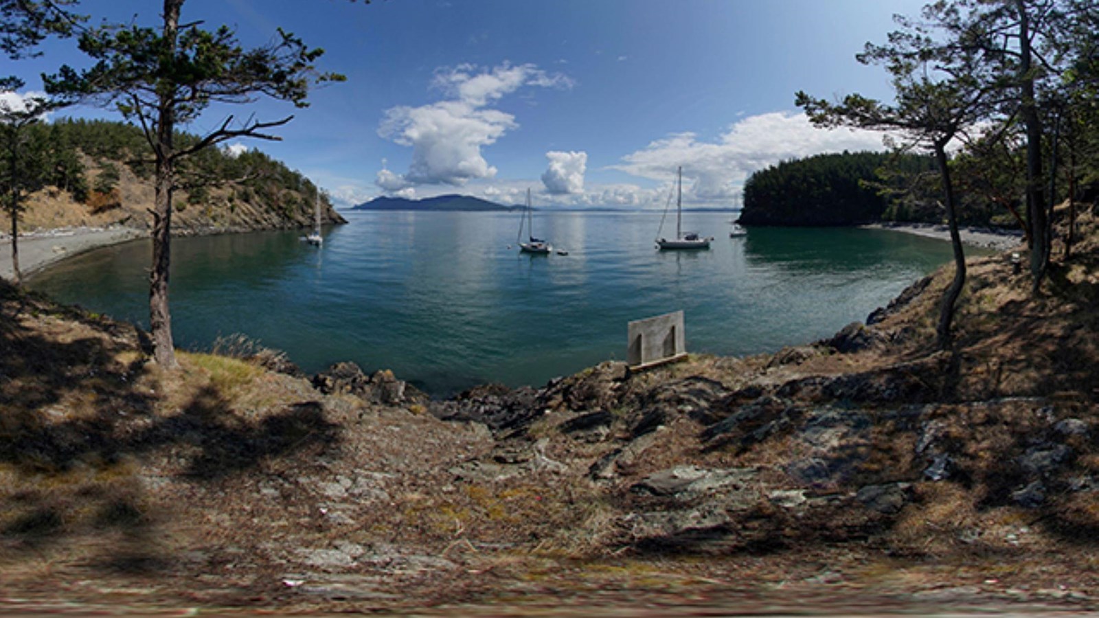 A waterside cove with multiple sailboats in the waters