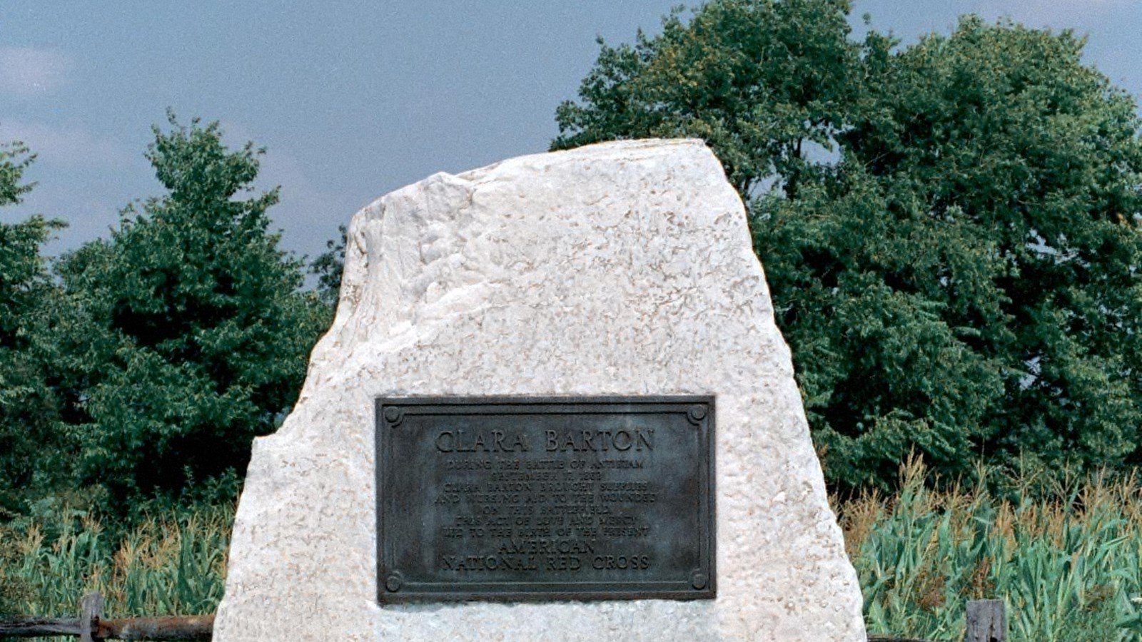 A stone monument with a plaque honoring Clara Barton. A small cross is inlayed on the base. 