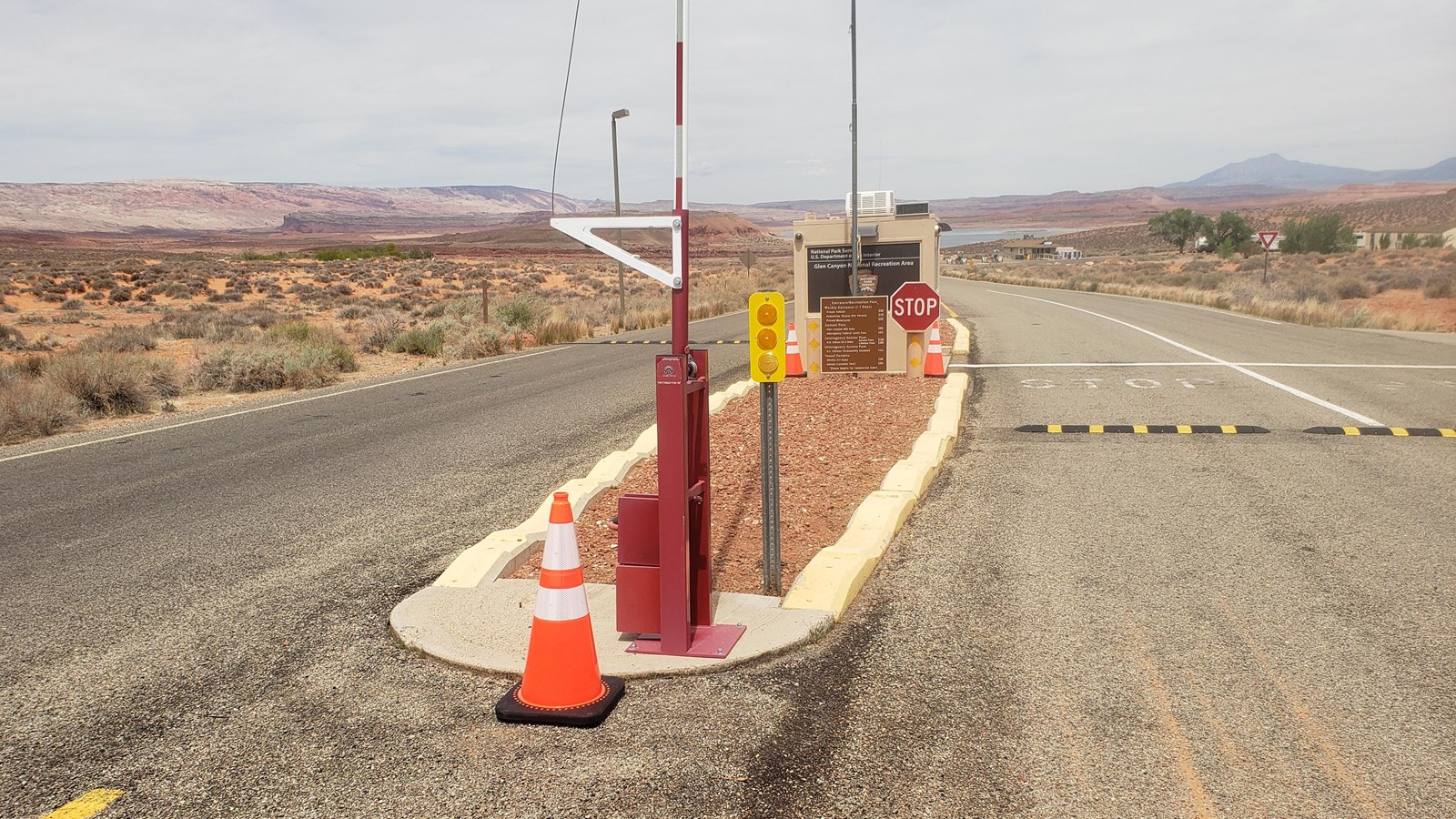 Asphalt road with orange cones along center lane. One windowed booth with arrowhead logo