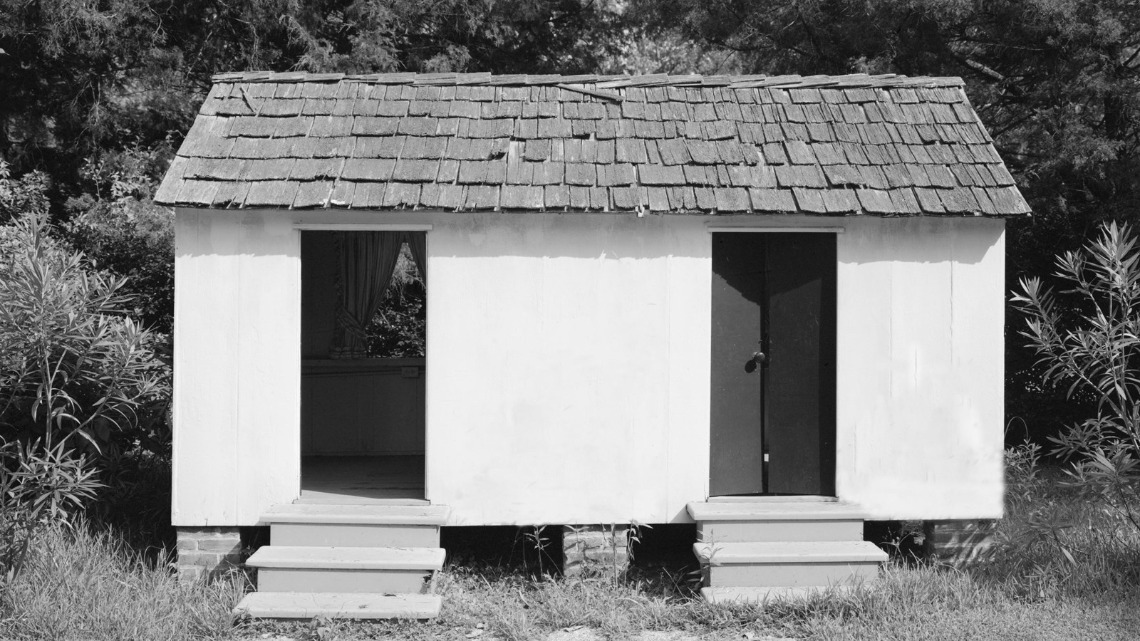 Child-size wood building with a wood shingle roof and two entryways