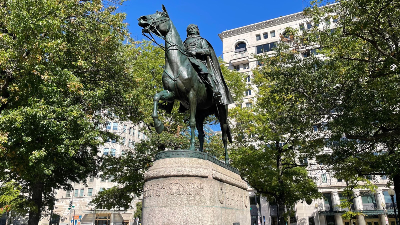 Bronze statue of a man on a horse in military uniform, mounted on a large stone pedestal