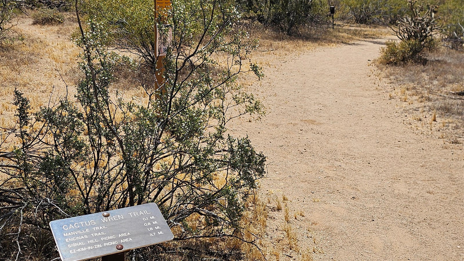 A small metal trail sign in the lower left reads