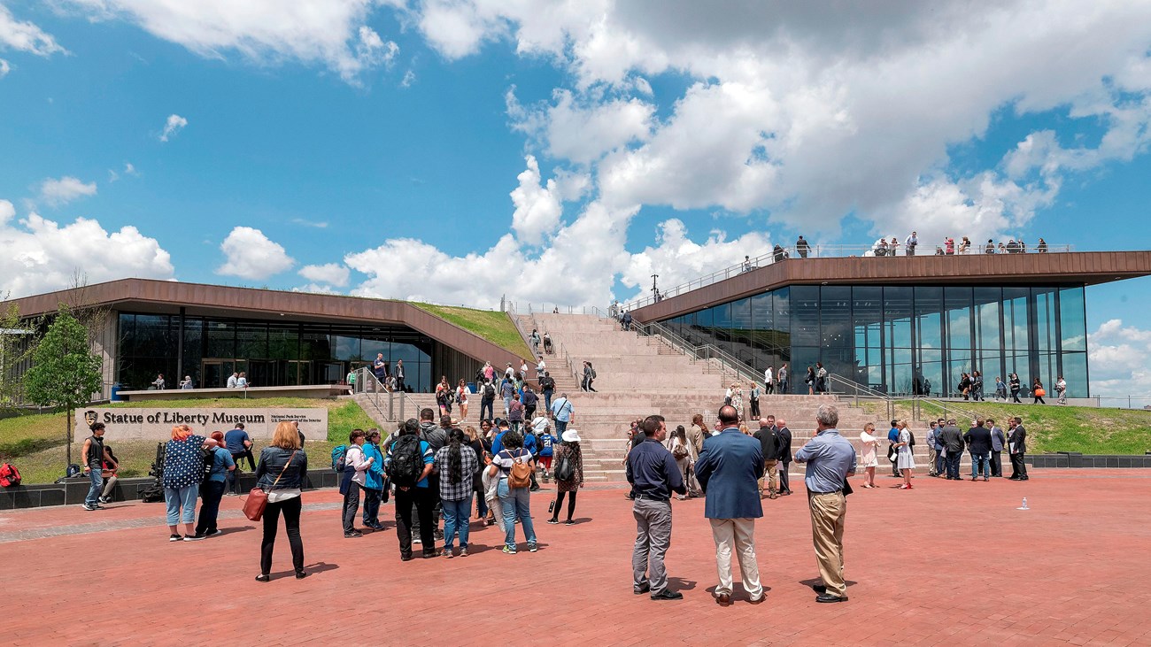The museum on Liberty Island with people congregating around it.