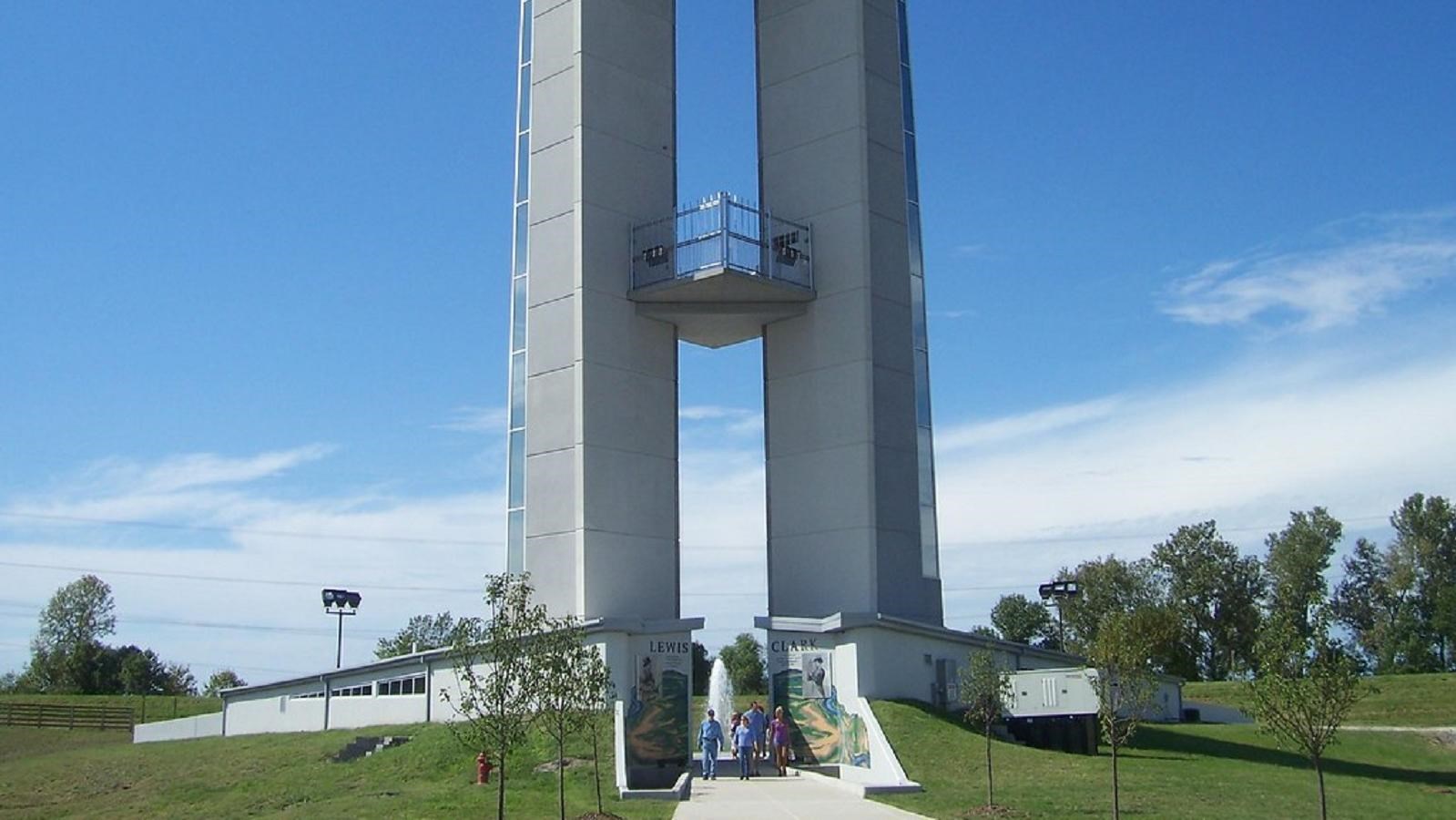 Two white spires stretch into the sky as visitors walk between them