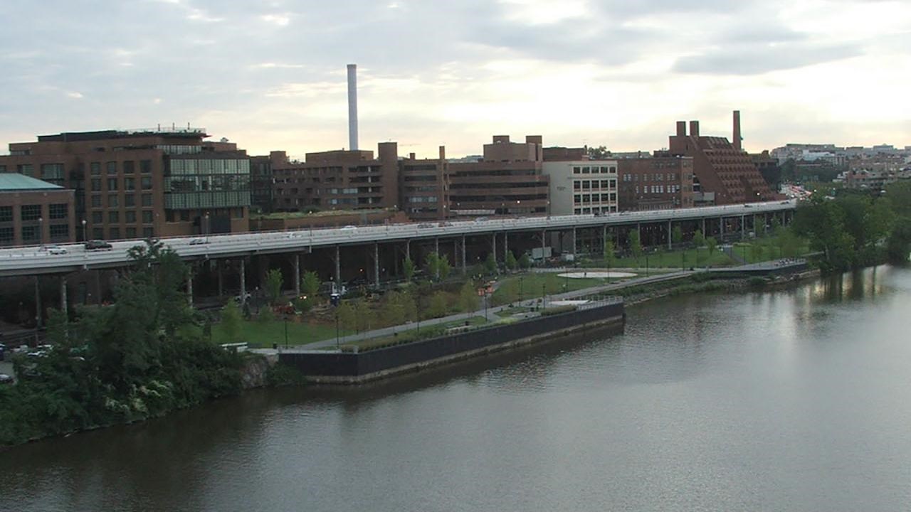 River, park and city skyline below a cloudy sky