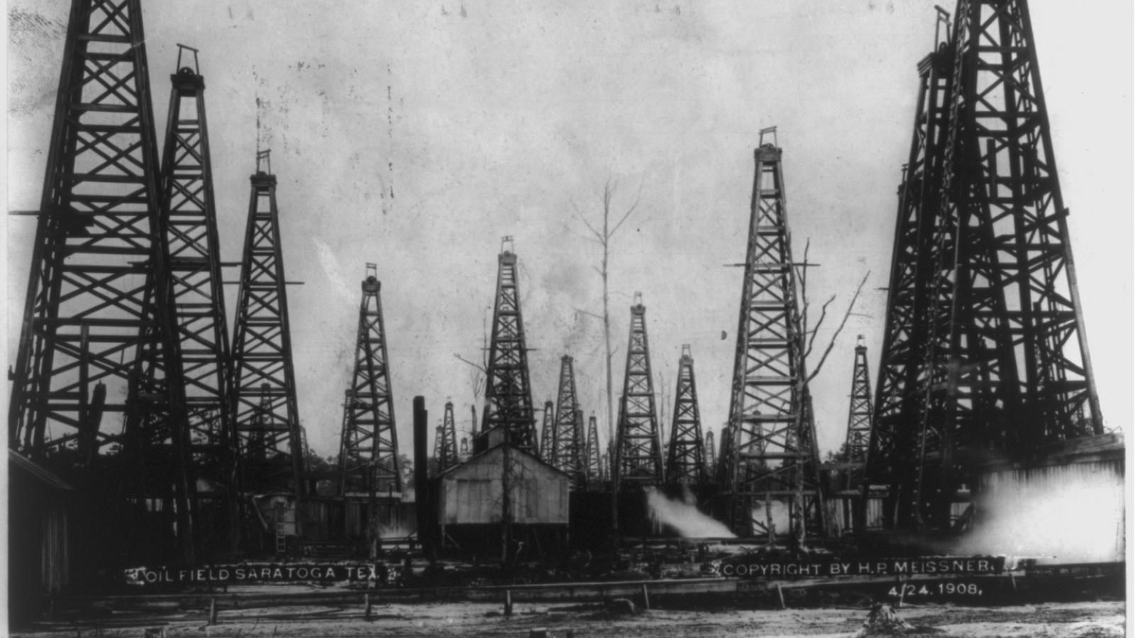 Historic photo of many tall wooden oil derricks. Text reads Oilfield Saratoga Tex. 4.24.1908