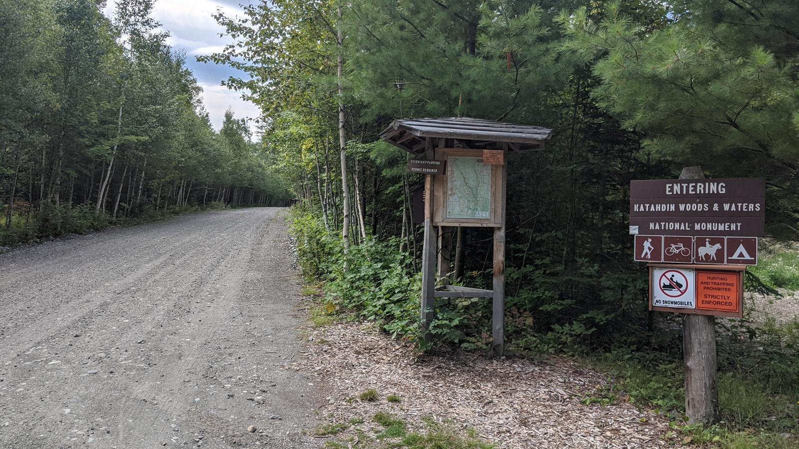 Brown wooden sign reads Entering Katahdin Woods and Waters National Monument. Map kiosk.