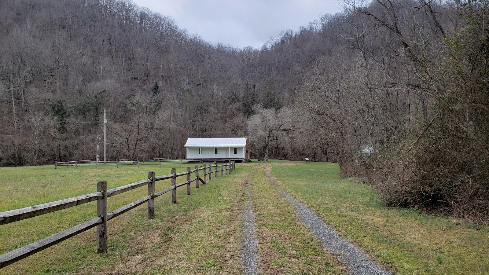 Farmhouse with field from the early 1900s. Farm is set back with view of a field and mountain.