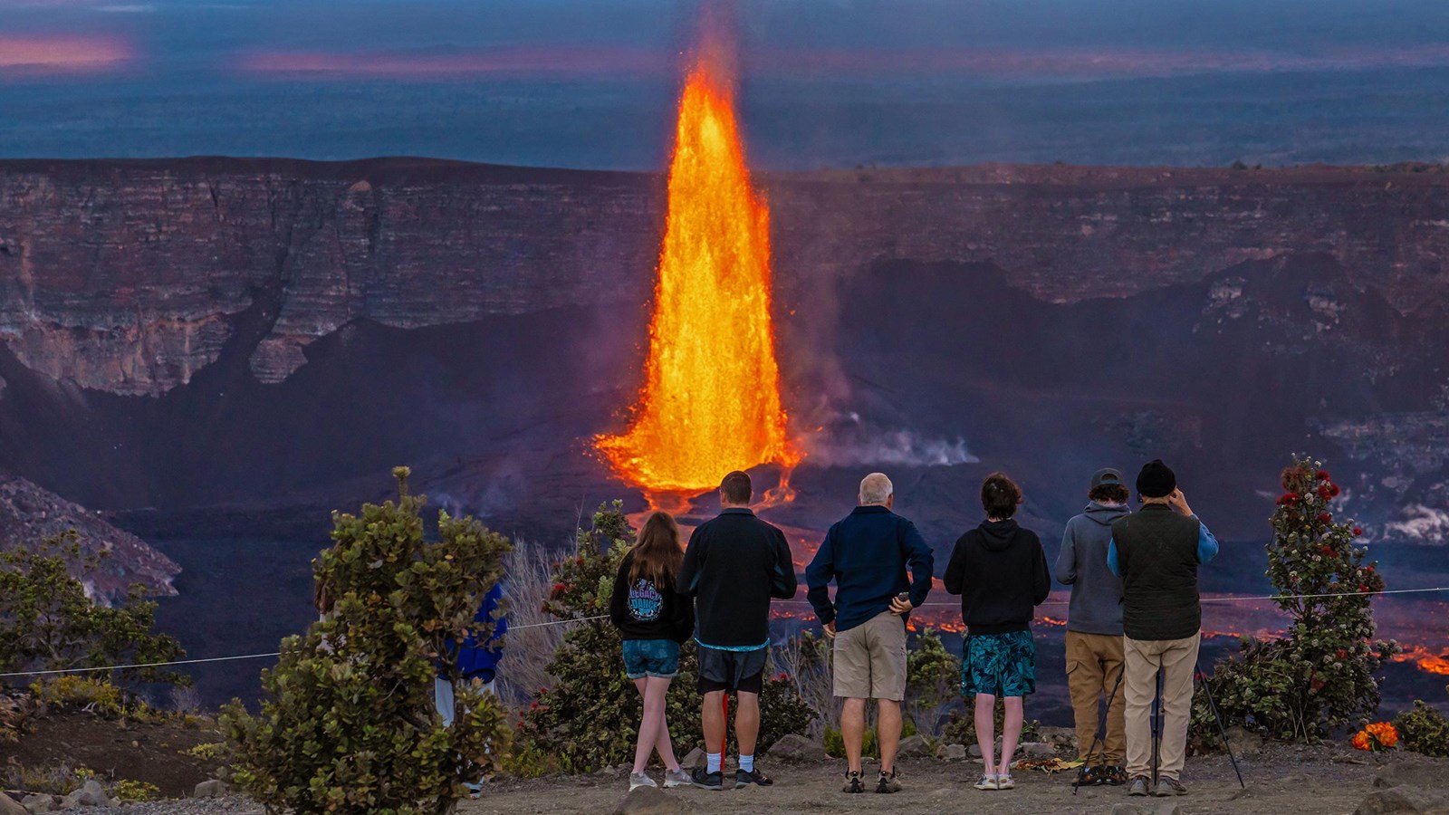 Visitors view an eruption within a crater.