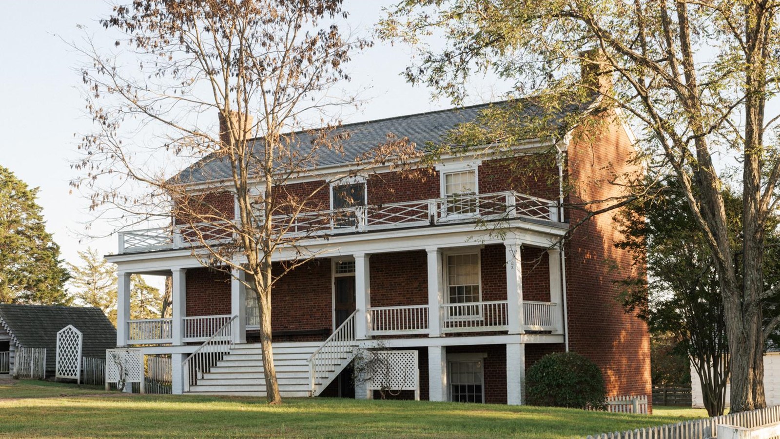 A front view of the McLean House- a 3 story brick home with a white porch lining the top two floors.